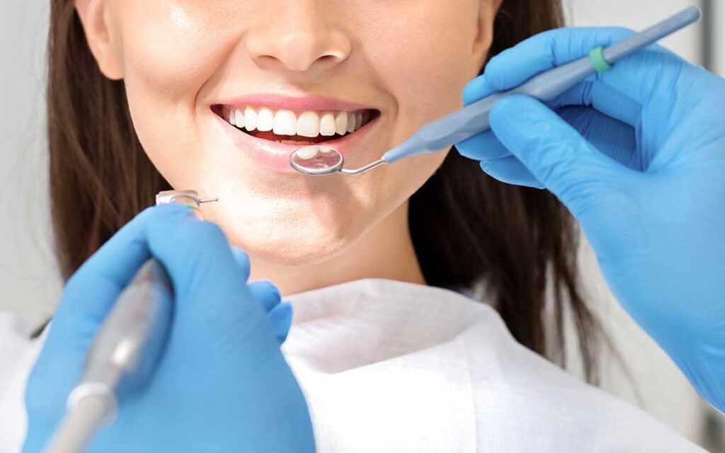 A person gently brushing their teeth at a bathroom sink with a soft-bristled toothbrush.