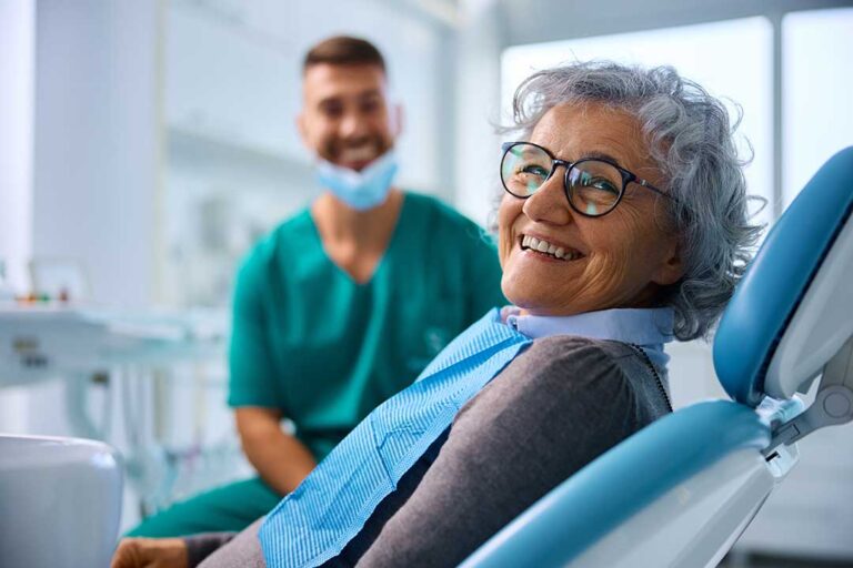 A dental hygienist reviews X-rays with a middle-aged patient during a routine checkup in a well-lit clinic.