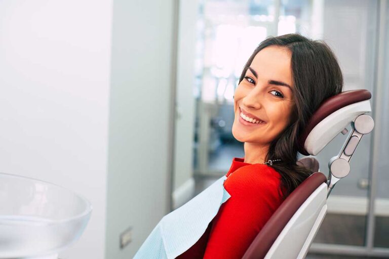 A dental hygienist gently cleaning a young adult’s teeth with professional dental instruments.