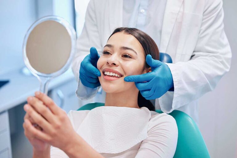 A person sitting in a dental chair, talking with a gentle dental hygienist before an exam.